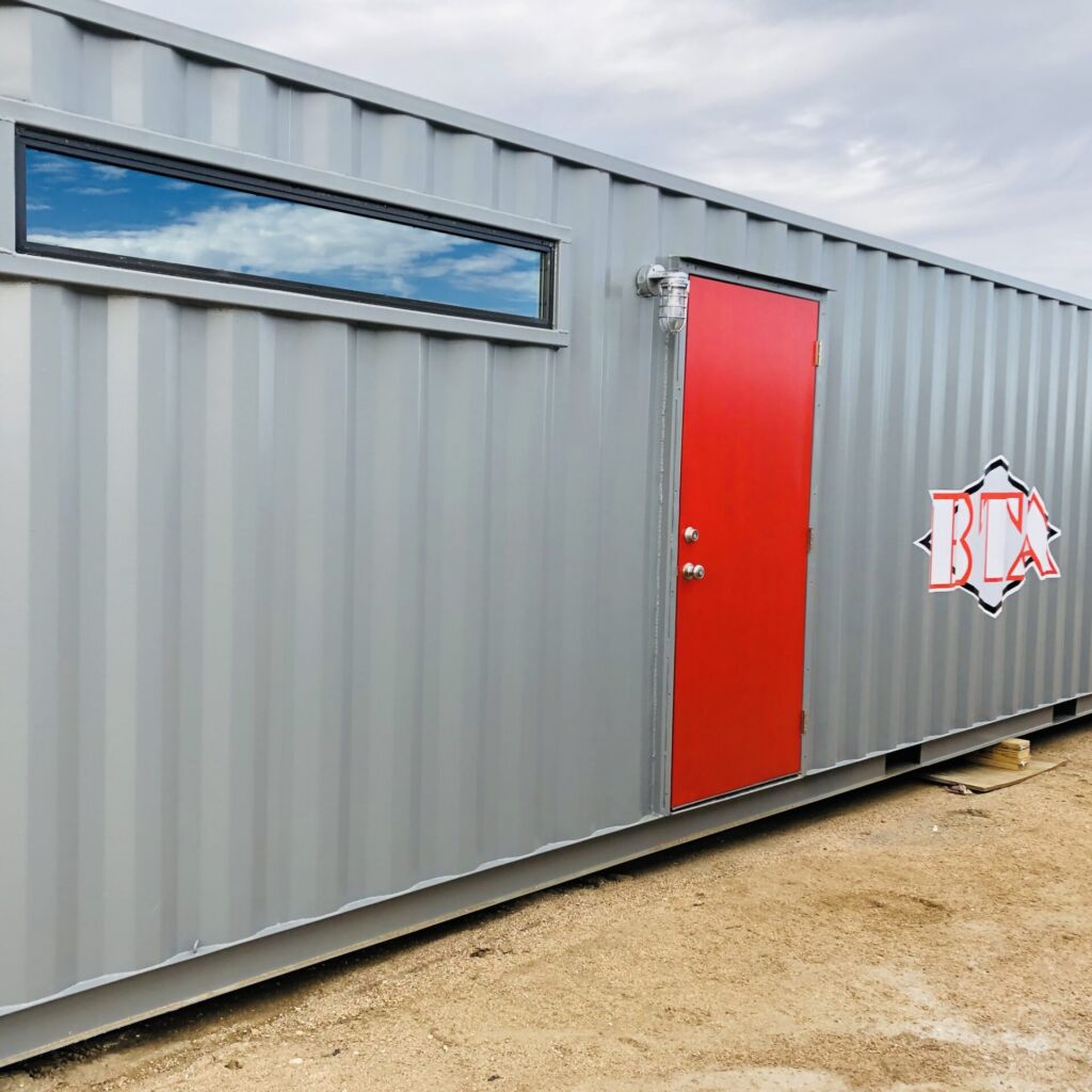A red door is on the side of a gray container.
