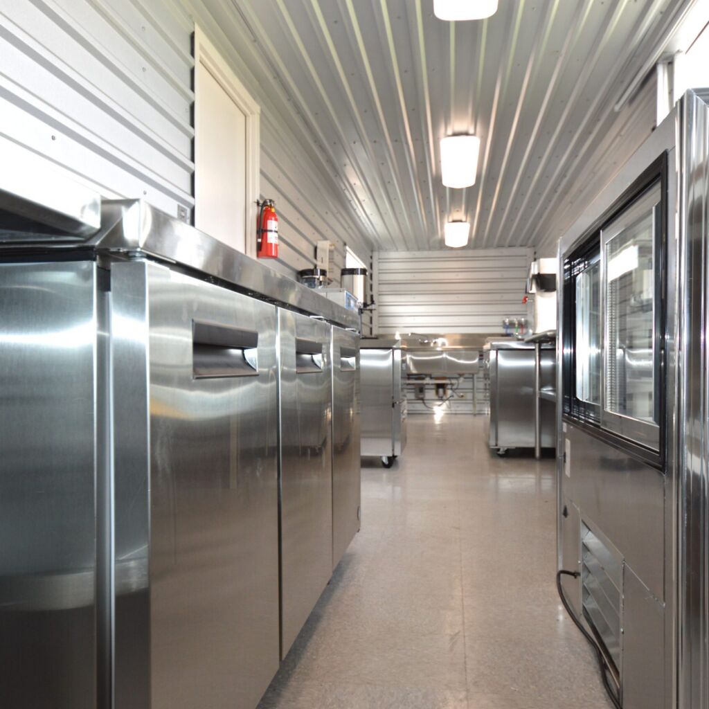 A long hallway with many stainless steel appliances.
