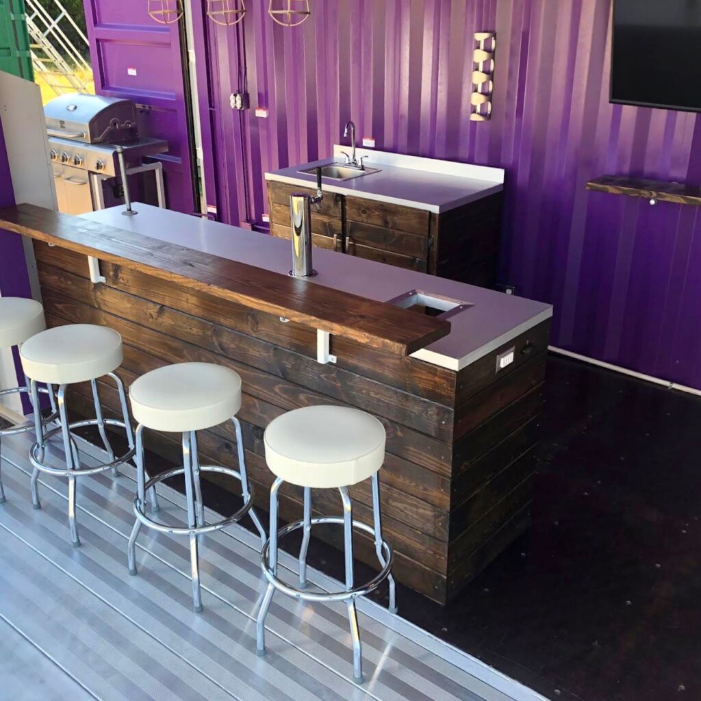 A bar with stools and a television on the wall.