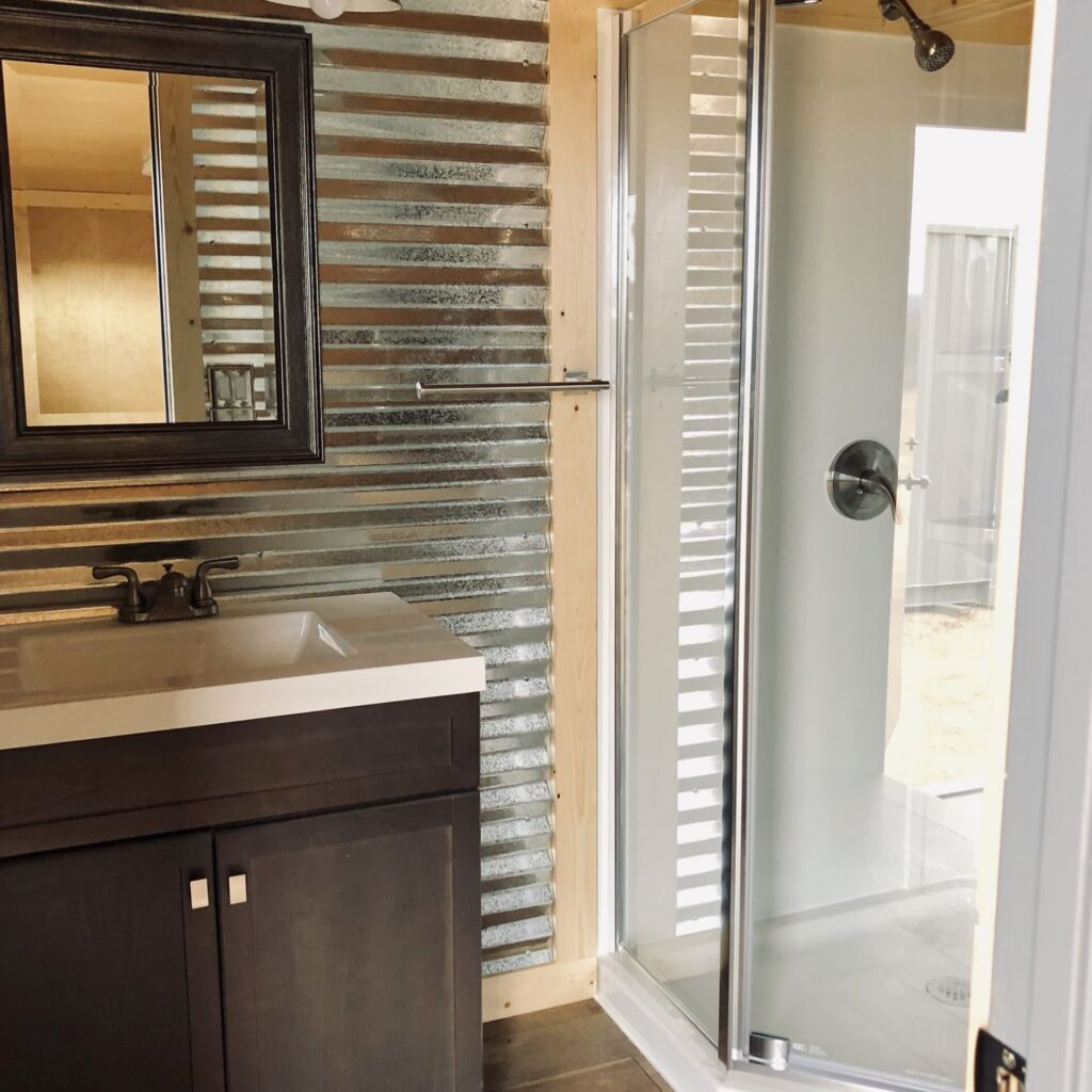 A bathroom with a sink, mirror and shower.