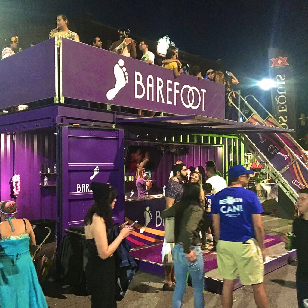 A group of people standing around a purple container.