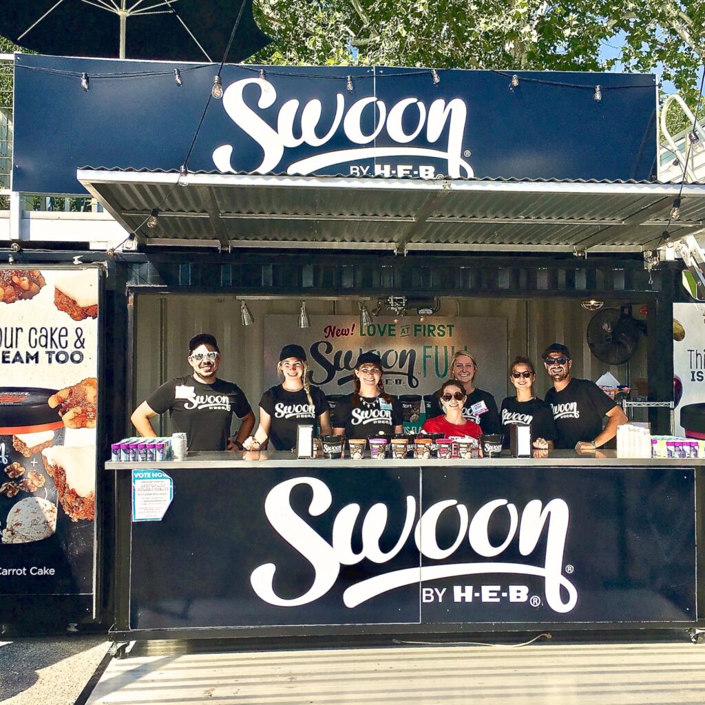 A group of people standing around a food stand.
