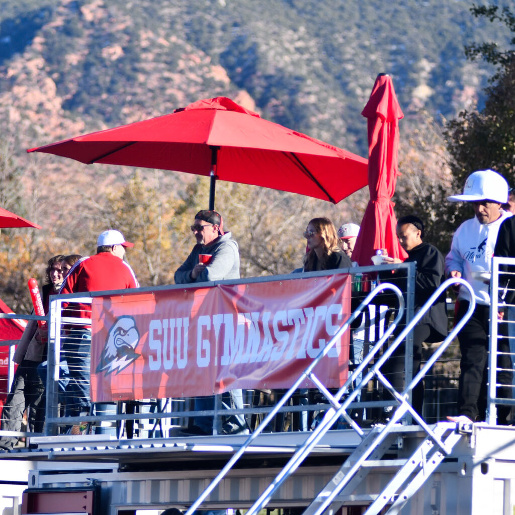 A group of people standing under umbrellas on top of a stadium.