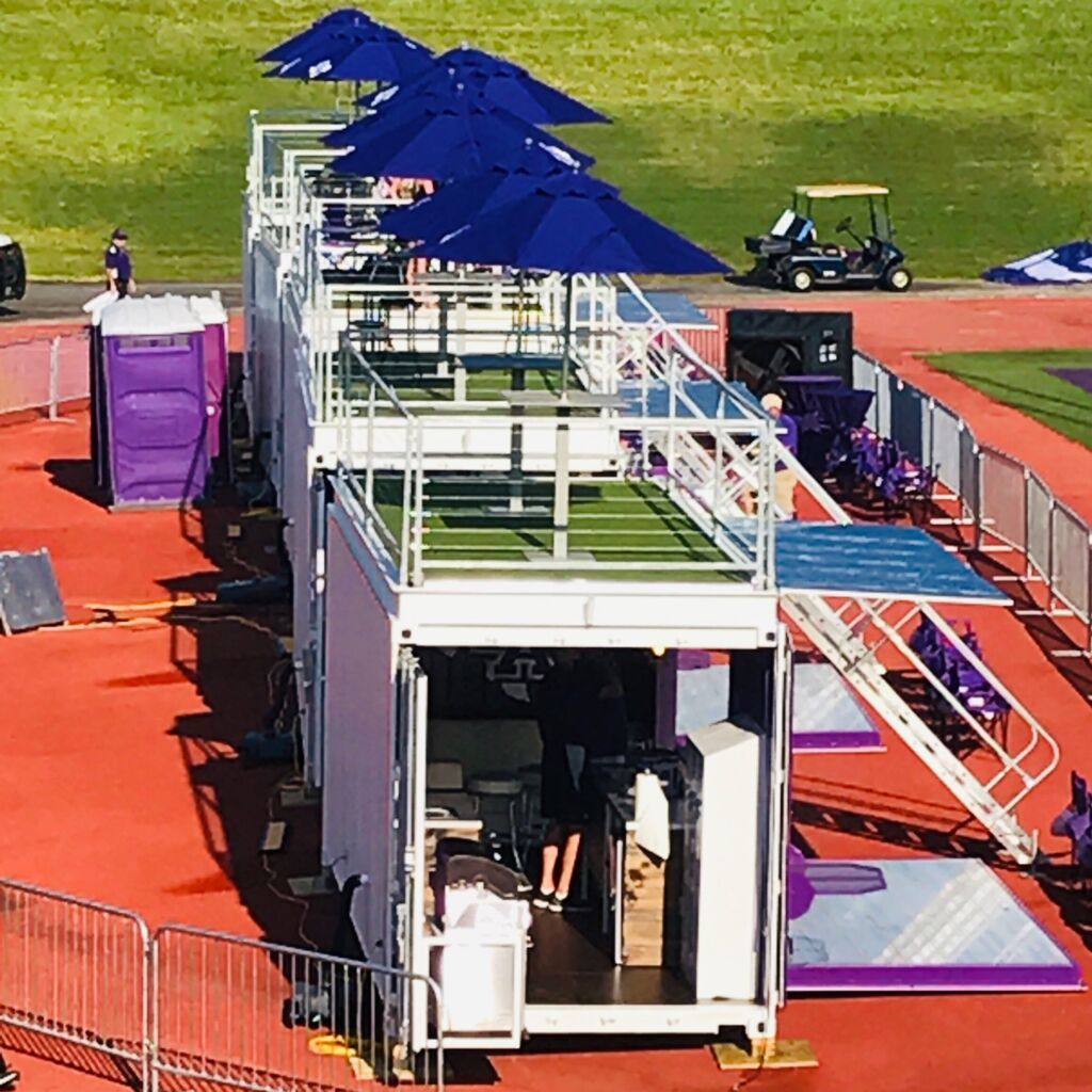 A row of blue umbrellas on top of an outdoor field.