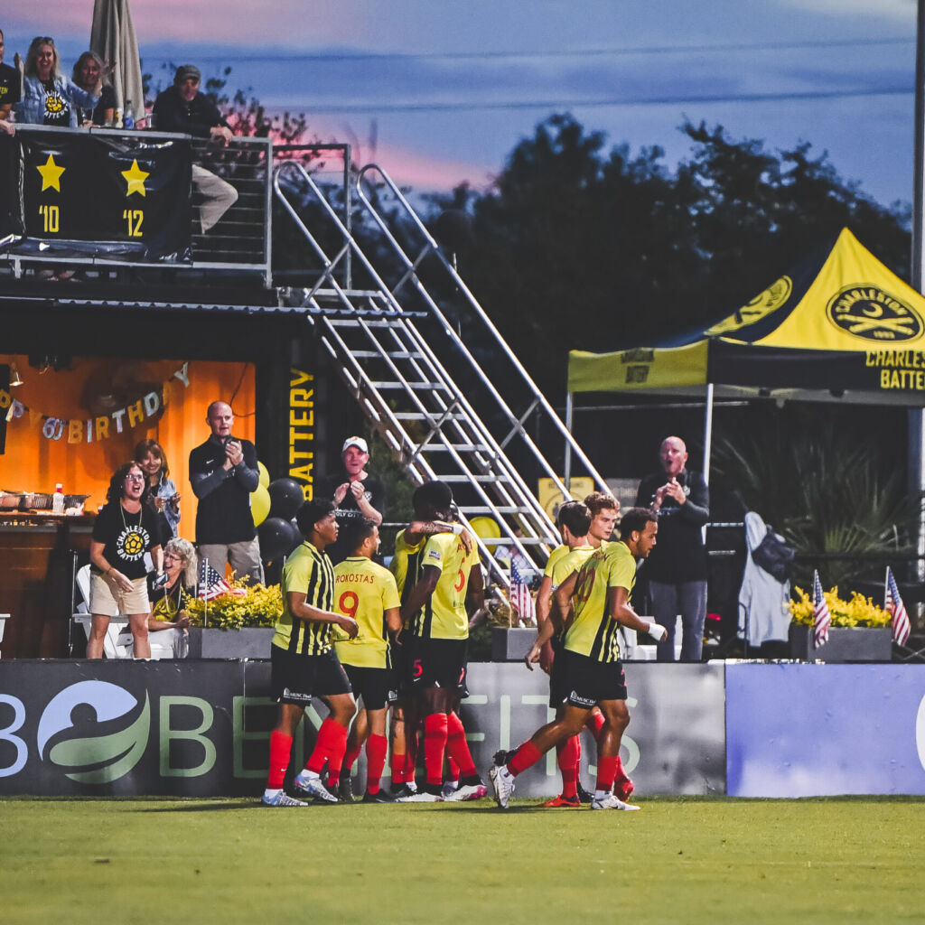 A group of people standing on top of a soccer field.