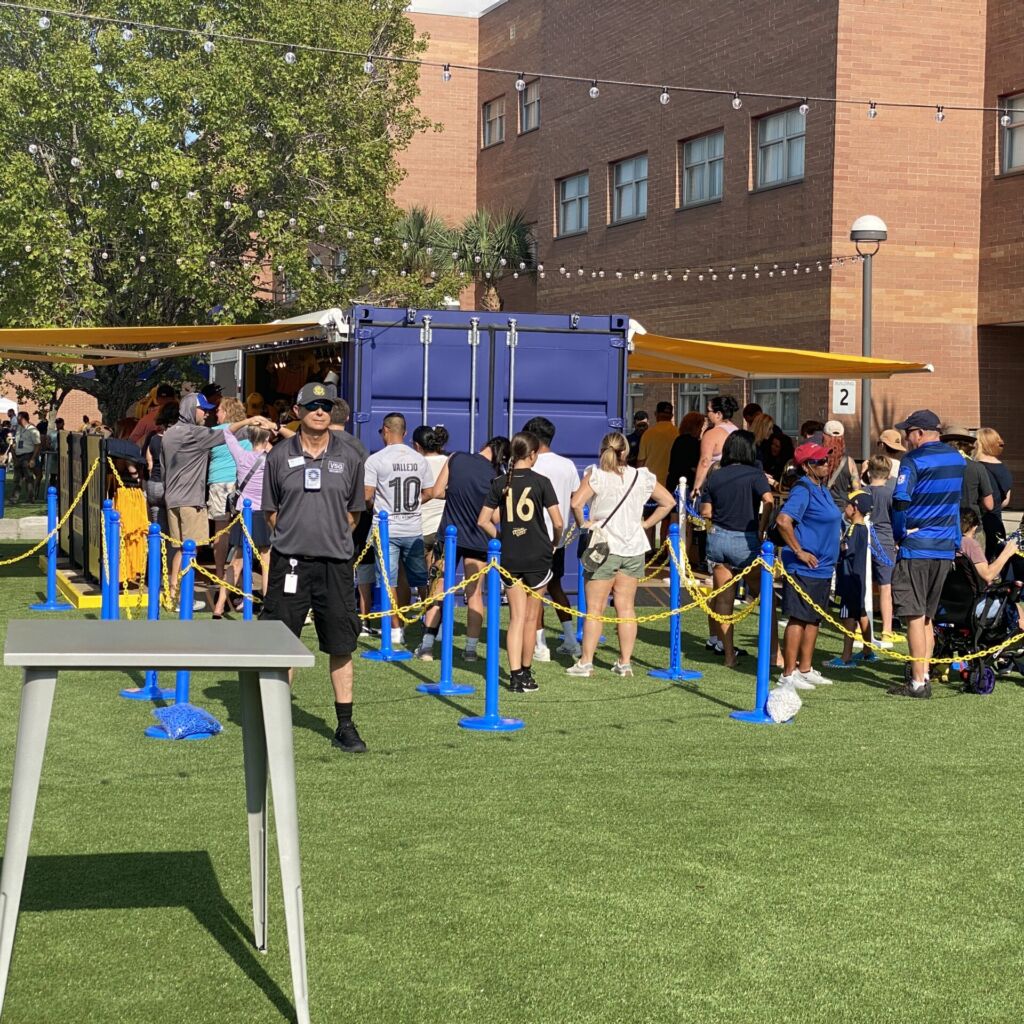 A group of people standing around in the grass.