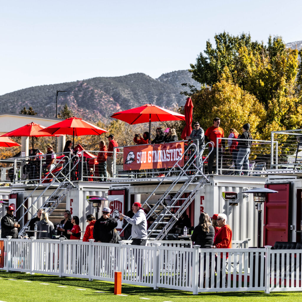 A crowd of people standing on top of a white fence.