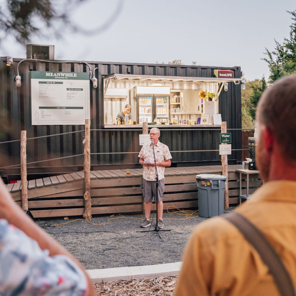 A man standing in front of people on a dirt road.