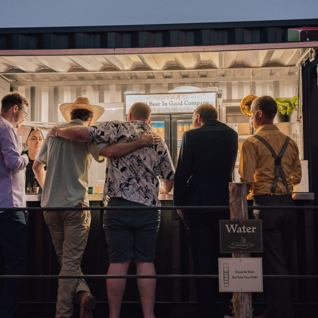 A group of people standing around a food stand.
