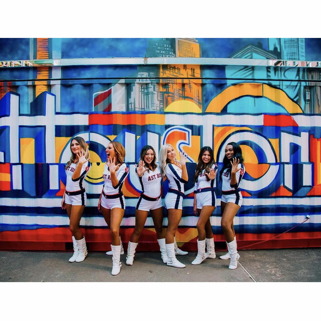 A group of cheerleaders standing in front of a wall.